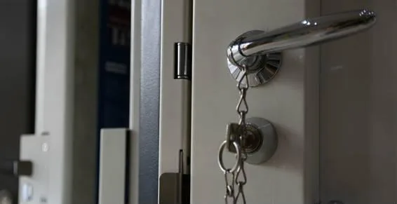 Béquille et cylindre chromés sur une porte blanche, clés sur la serrure